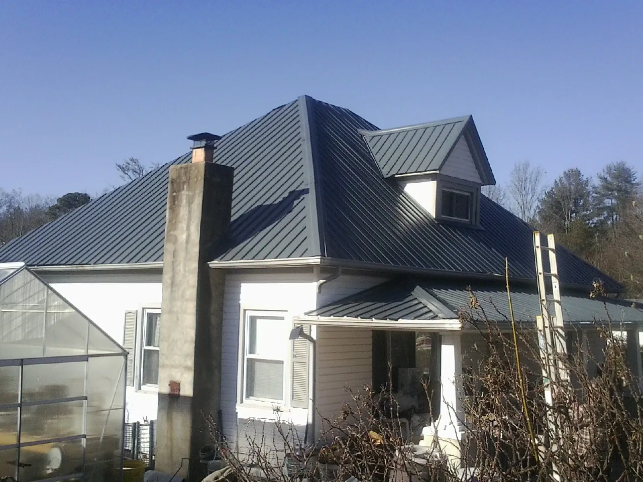 Dark blue standing seam metal roof on a white farmhouse with dormer — Slate & Tile Roof Repair by Roofing Brothers in Bethune