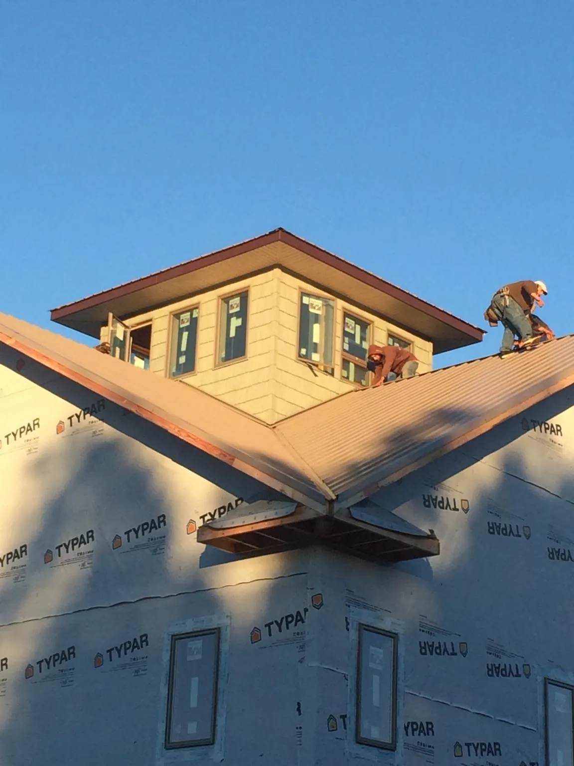 Roofers working around a rooftop cupola on a new metal roof at sunset — Roof Waterproofing in Bethune by Roofing Brothers